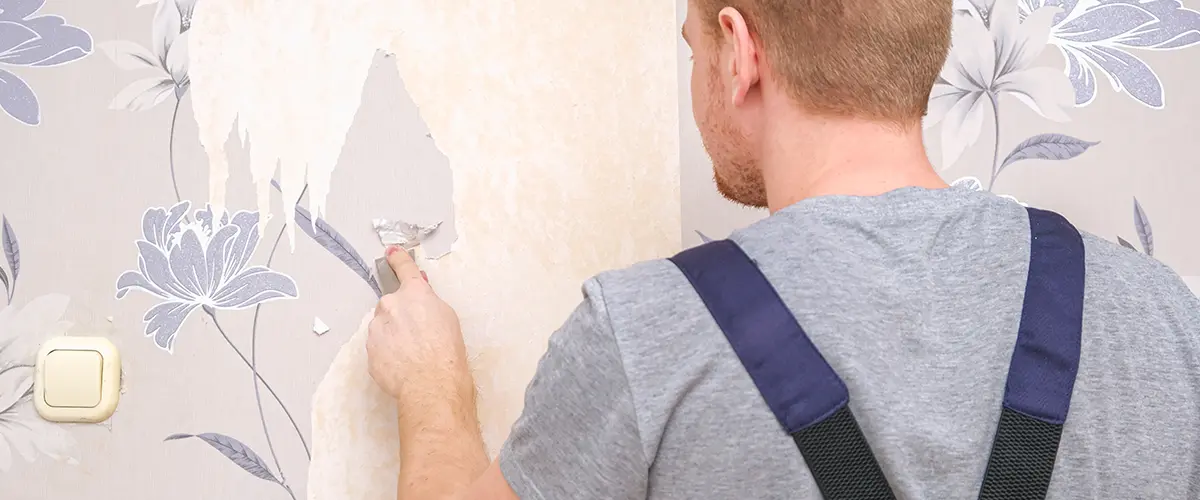 Man peeling off old wallpaper in preparation for painting over wallpaper