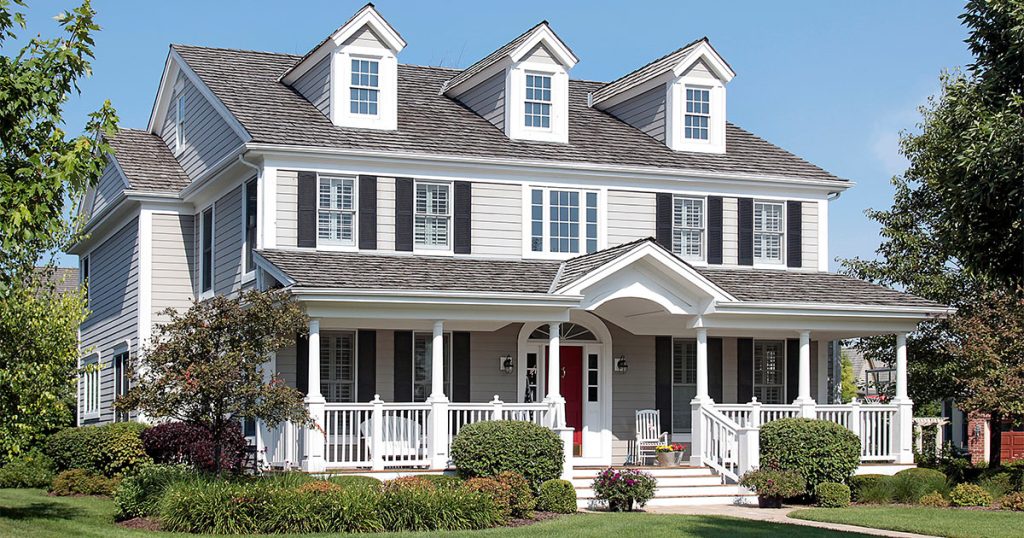 Large mansion with white siding with railing and a porch