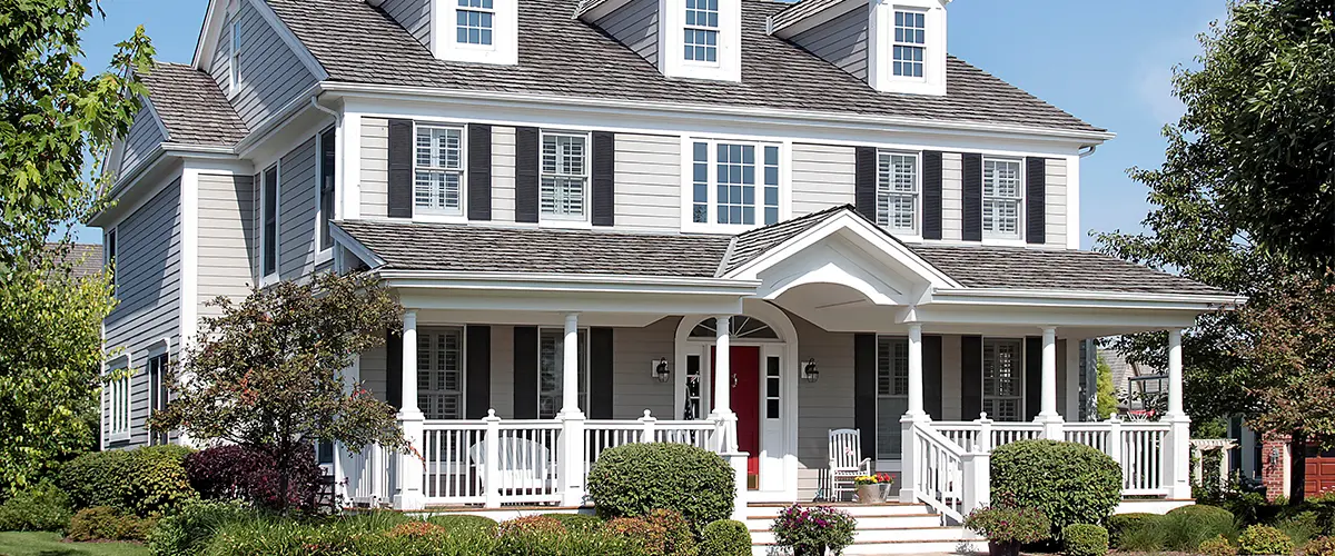 Large mansion with white siding with railing and a porch