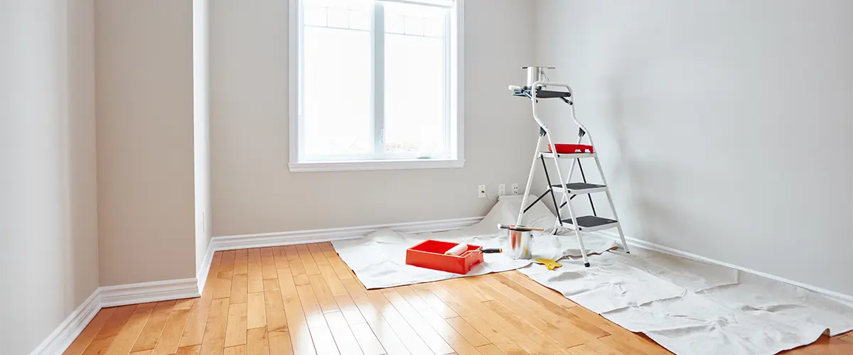 Interior painting, a ladder and painting tools on the floor.