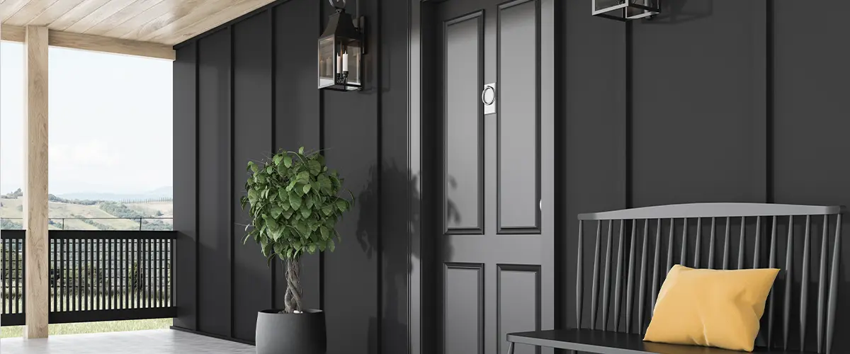 Modern home entrance with black doors and walls and cozy outdoor seating.