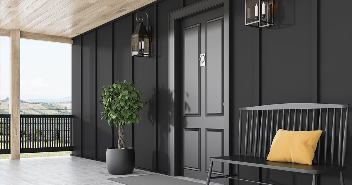 Modern home entrance with black doors and walls and cozy outdoor seating.