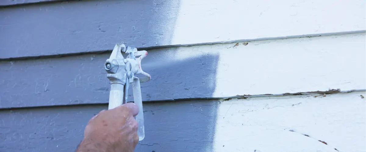 person exterior painting a house in white