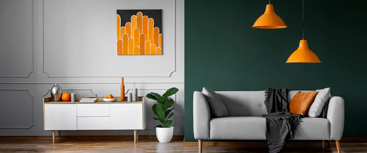 Modern interior painting project in Fairfax, with gray sofa, orange accents, green accent wall, wooden floor, and stylish decor including a plant and artwork.