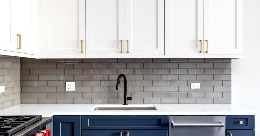 Modern kitchen interior design with white cabinets, subway tile backsplash, and navy blue lower cabinets