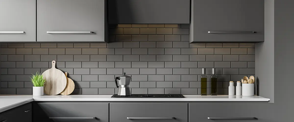 Modern kitchen with matte gray cabinets, subway tile backsplash, and minimalist countertop with kitchen accessories.