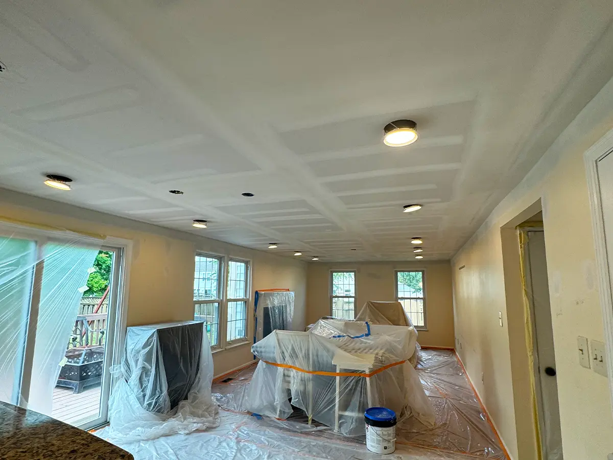 Completed drywall installation with ceiling lighting in a protected room ready for interior painting.