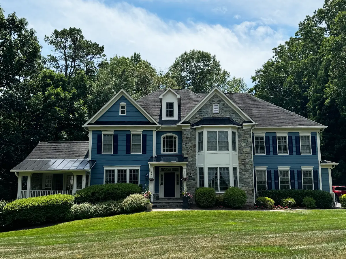 Stately blue and stone two-story house with large front lawn and professional landscaping.