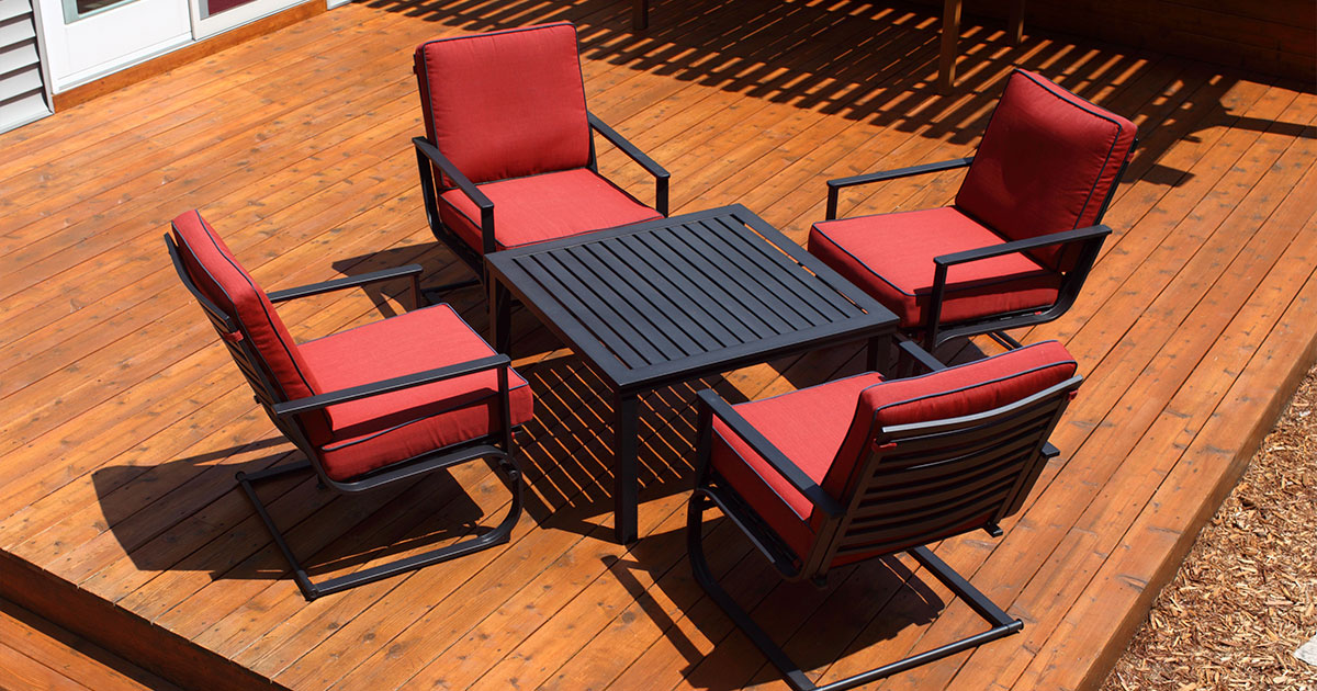 Wooden deck with black metal patio furniture and red cushions, ideal for outdoor living space and relaxation.