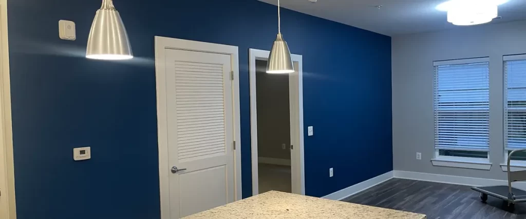 Modern interior with blue accent wall, pendant lighting, white doors, and granite kitchen island