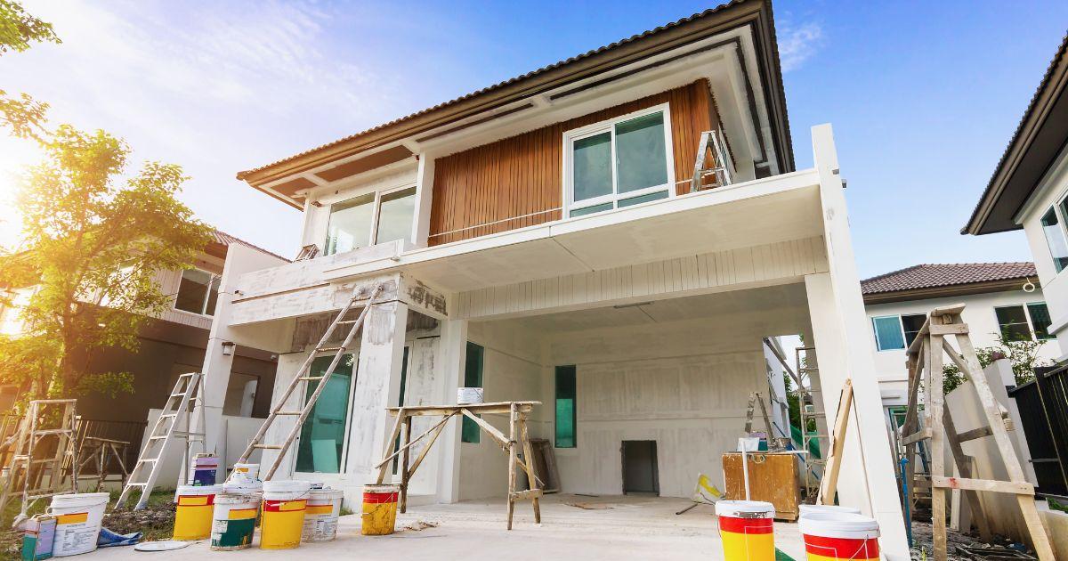 Modern two-story home being prepped for exterior painting with ladders and paint buckets