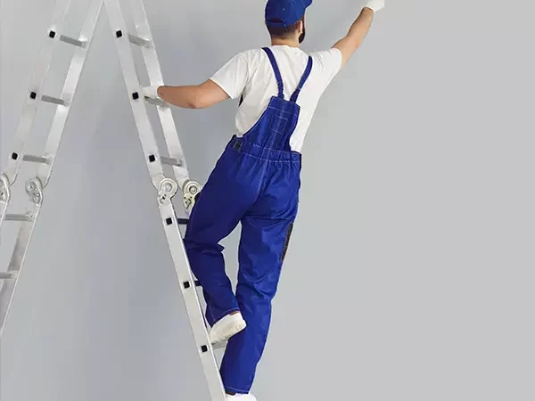 Man on a ladder painting a wall.